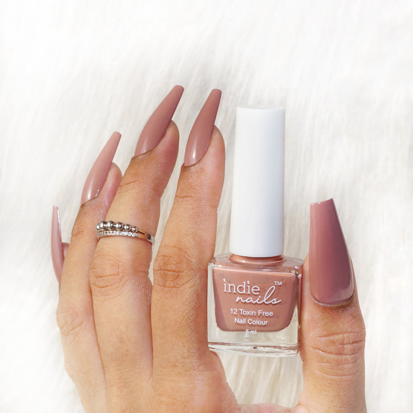 Lifestyle image of model wearing nude brown nail polish (Cutting Chai)